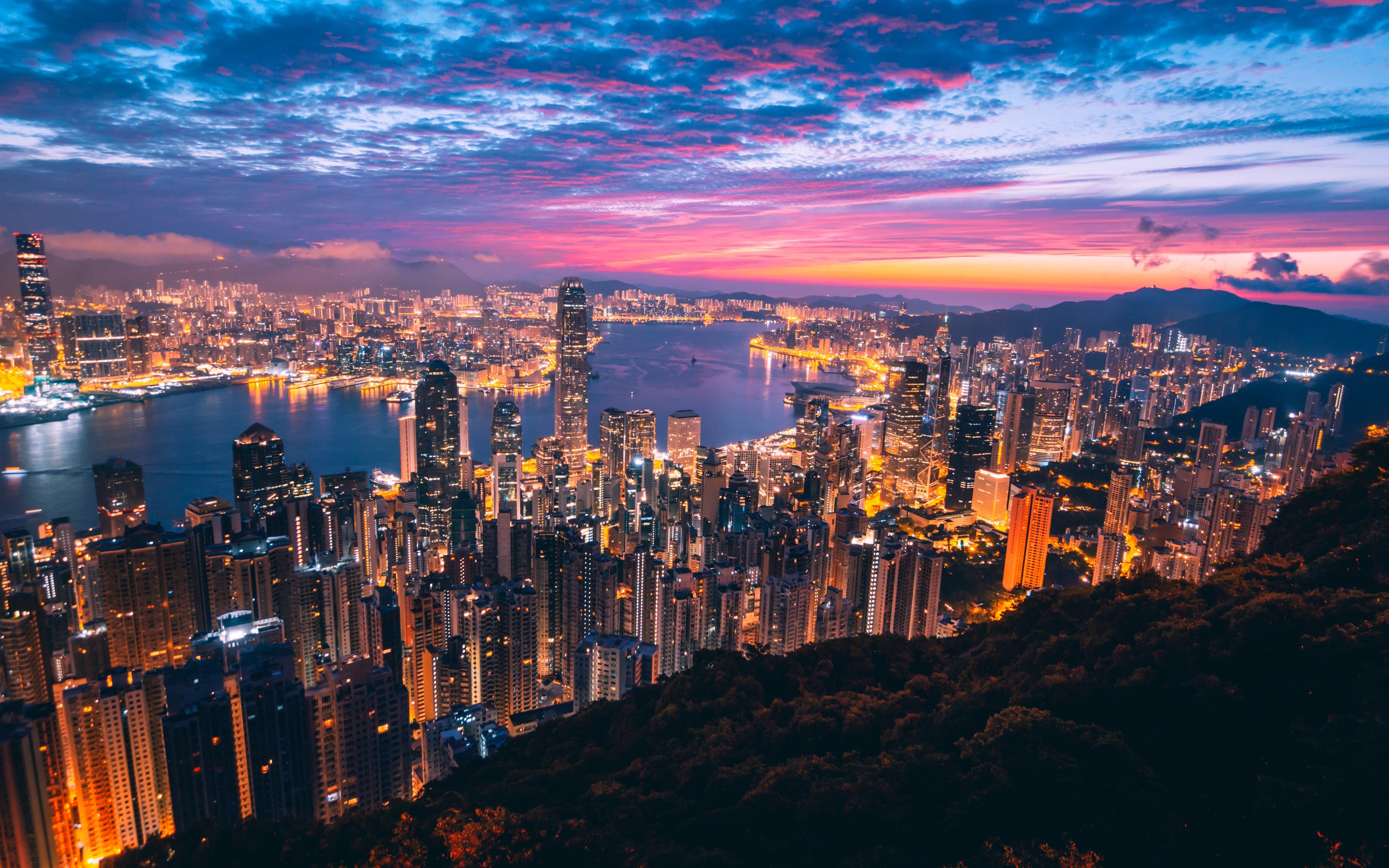 Überblick über die beleuchtete Stadt mit buntem Himmel im Hintergrund in Hongkong