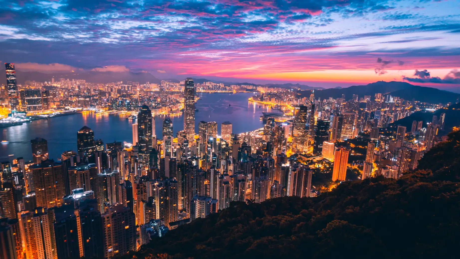 Überblick über die beleuchtete Stadt mit buntem Himmel im Hintergrund in Hongkong