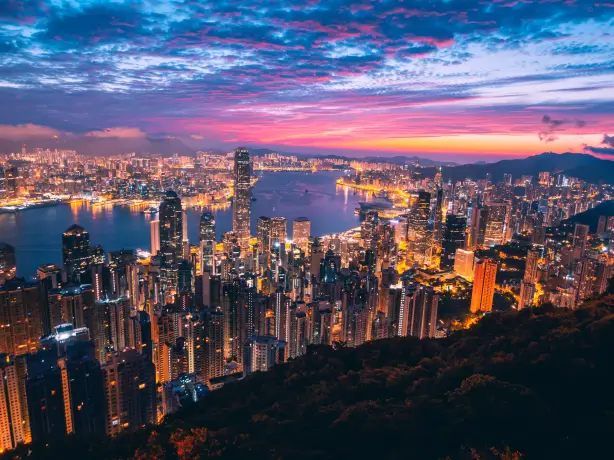 Overzicht van de verlichte stad met kleurrijke lucht op de achtergrond in Hong-Kong