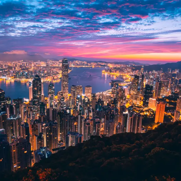 Überblick über die beleuchtete Stadt mit buntem Himmel im Hintergrund in Hongkong