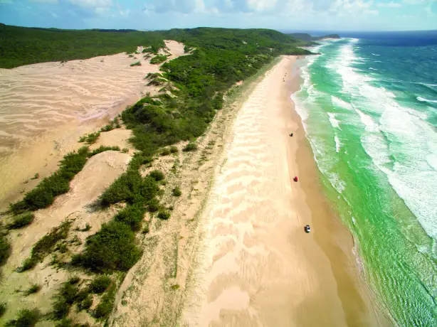 Der größte Sandstrand der Welt auf Fraser Island mit Dünen links und dem türkisgrünen Meer rechts