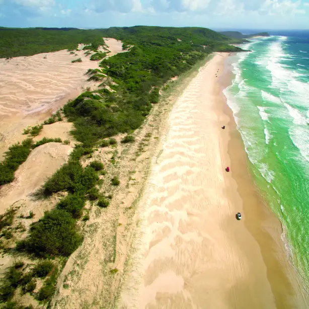 Der größte Sandstrand der Welt auf Fraser Island mit Dünen links und dem türkisgrünen Meer rechts