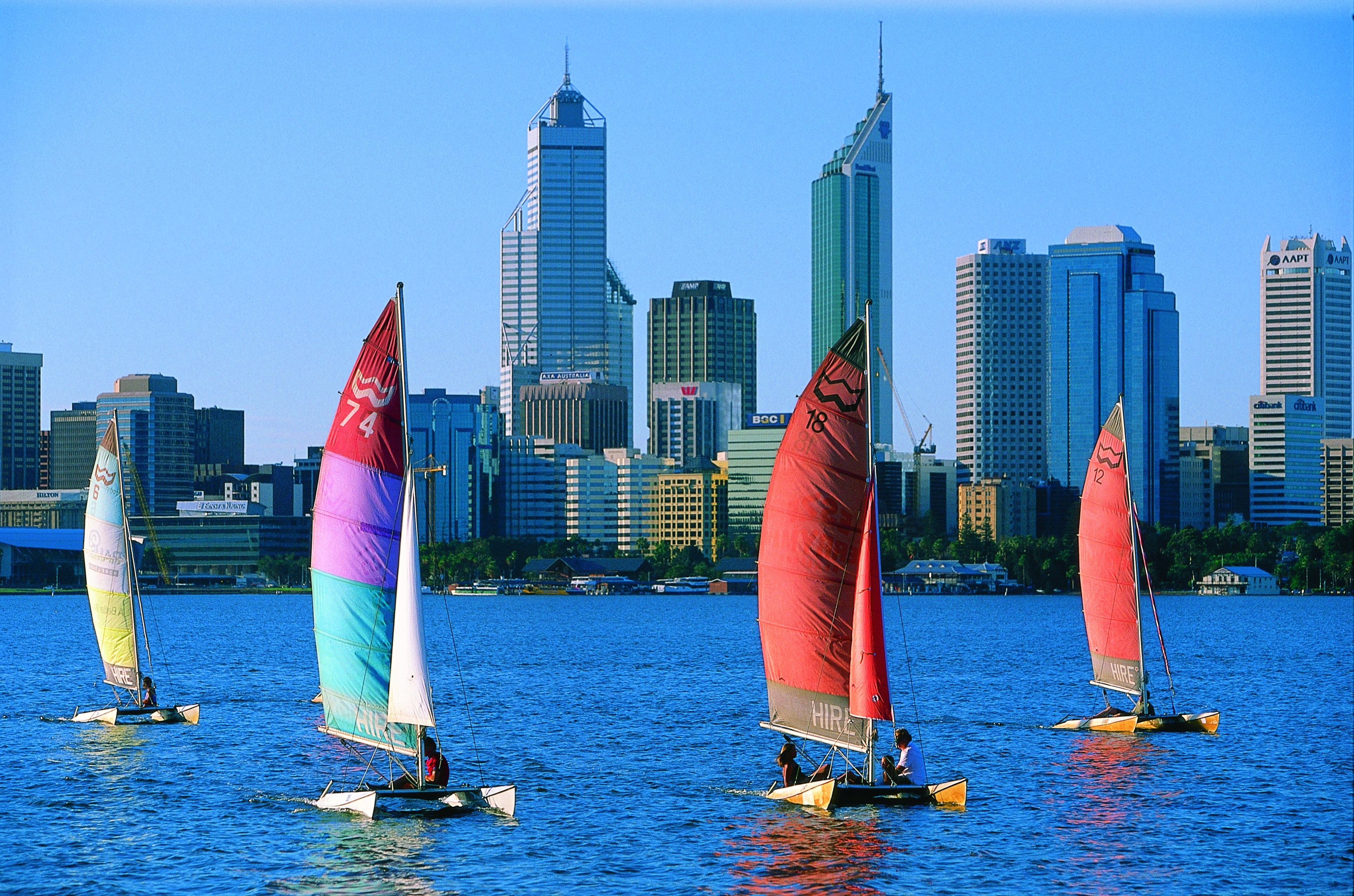 Katamarane mit bunten Segeln gleiten an der Skyline der Stadt Perth in Westaustralien vorbei.