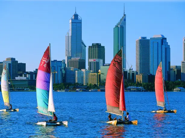 Katamarane mit bunten Segeln gleiten an der Skyline der Stadt Perth in Westaustralien vorbei.