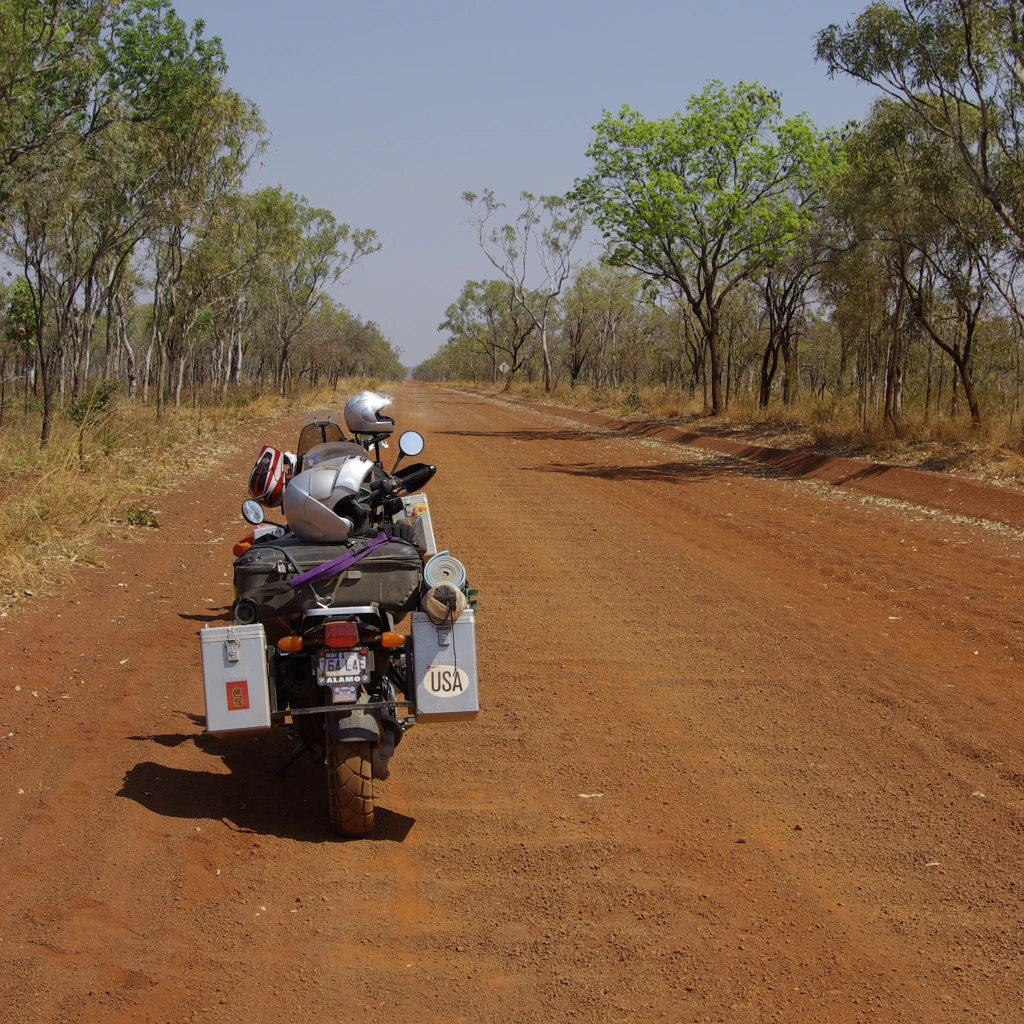 Een bepakte motor op een onverharde, rode weg in Australië