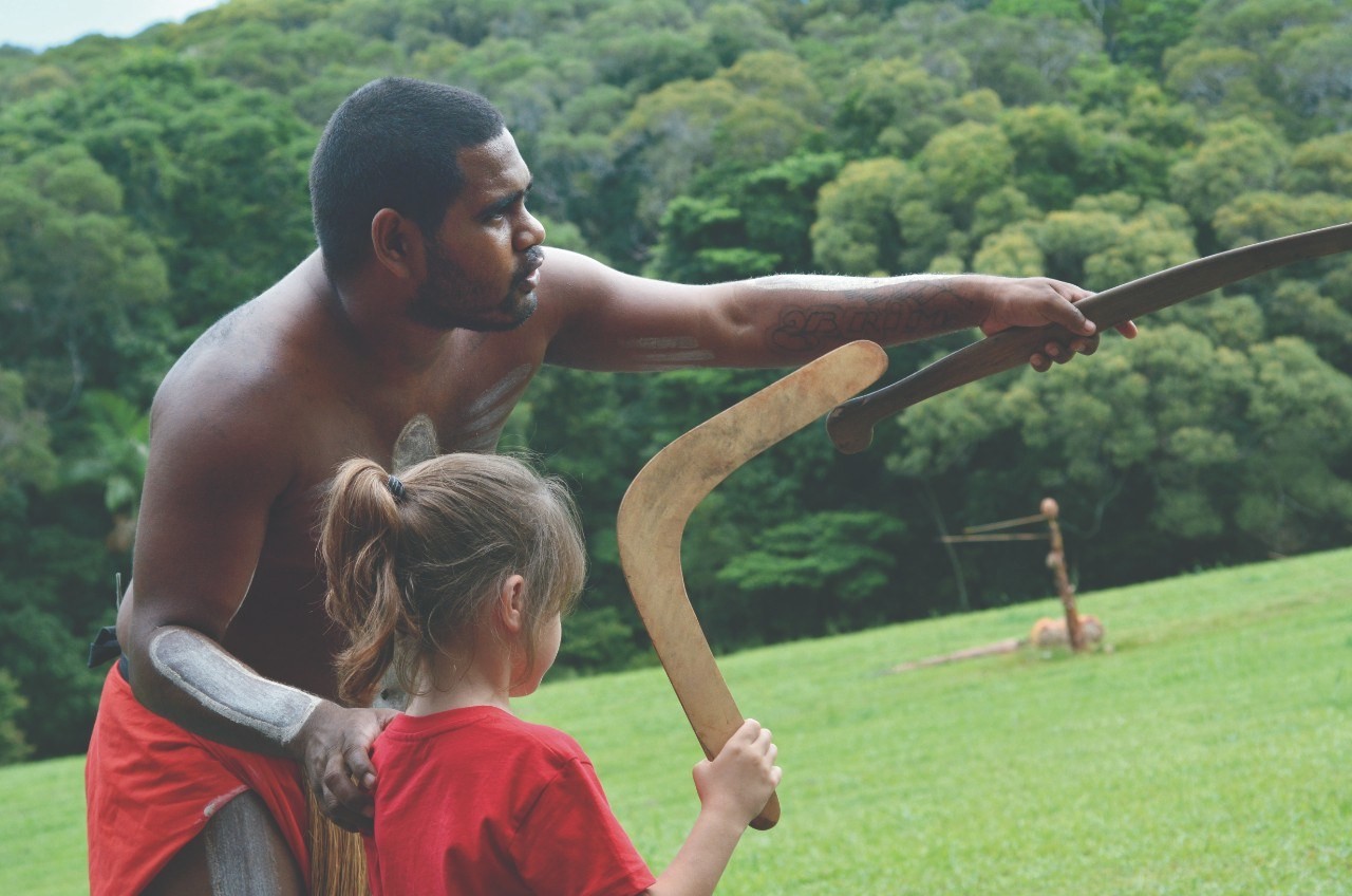 Aborigine-Mann lehrt Kind den Umgang mit einem Bumerang