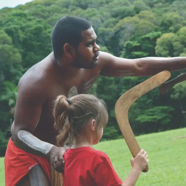 Aborigine-Mann lehrt Kind den Umgang mit einem Bumerang