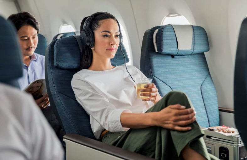 Frau sitzt mit Getränk in Cathay Pacific Premium Eco