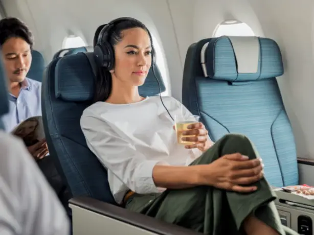 Frau sitzt mit Getränk in Cathay Pacific Premium Eco