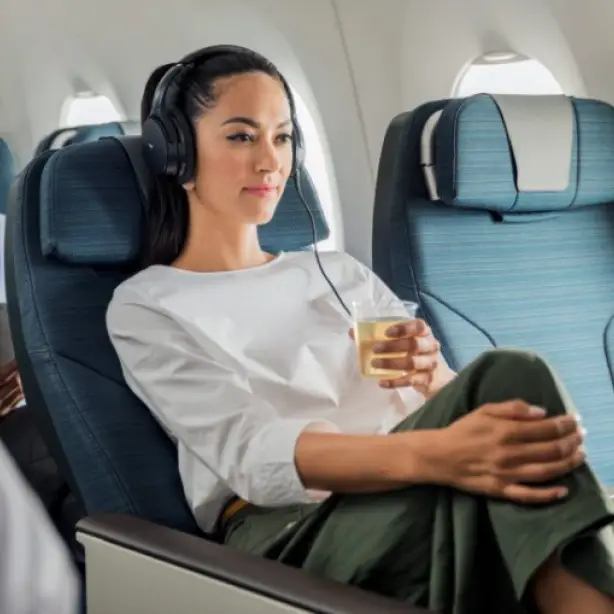 Frau sitzt mit Getränk in Cathay Pacific Premium Eco