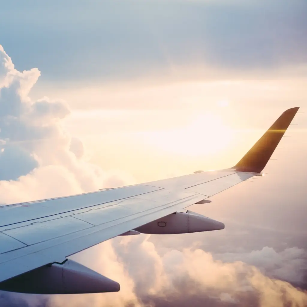 View of a planes wing from window above the clouds