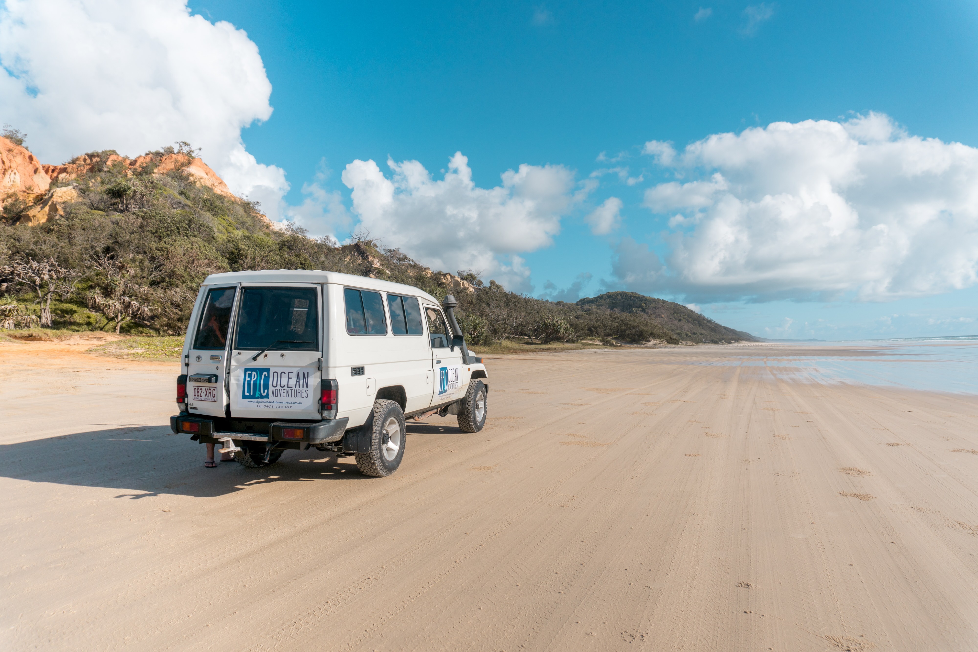 Een witte 4WD rijdt over het strand