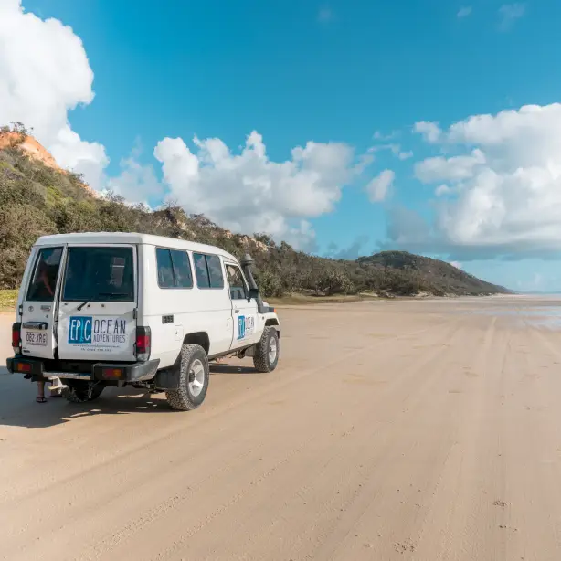 Ein weißer Geländewagen fährt am Strand