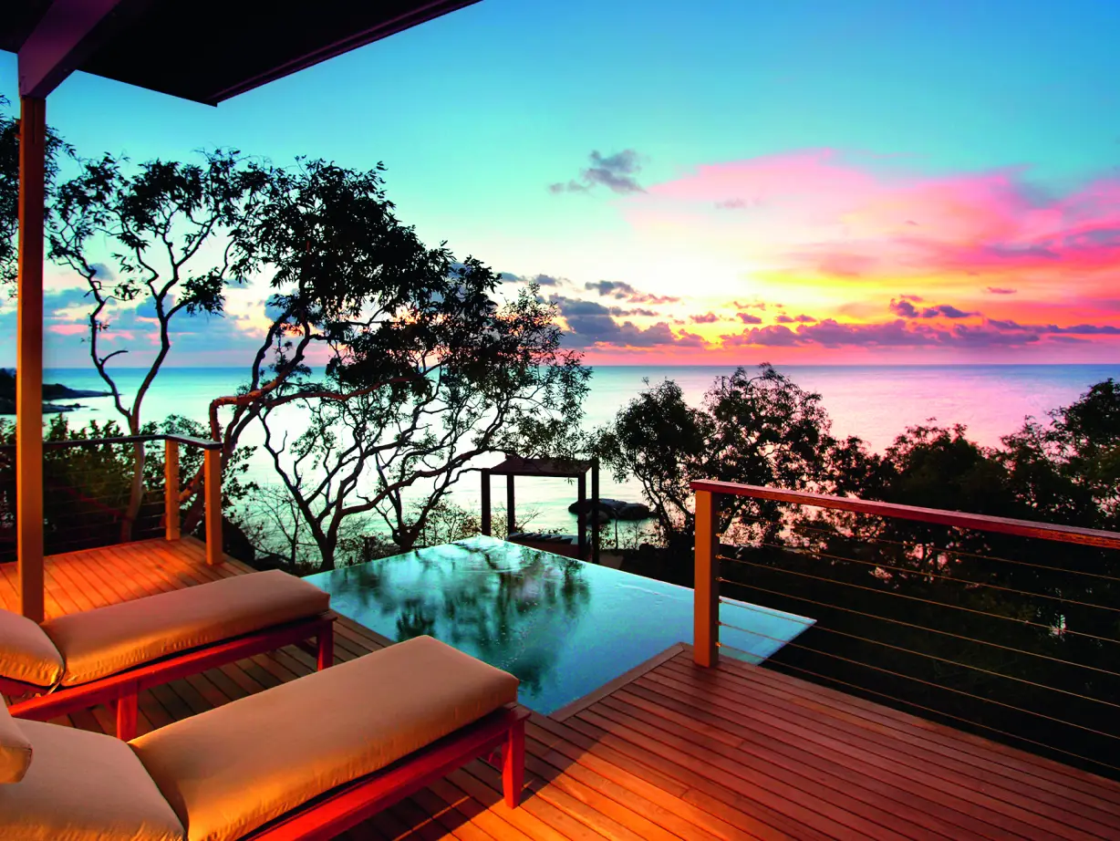 Liegestühle auf einer Terrasse mit Swimmingpool, bunter Himmel im Hintergrund - Australien