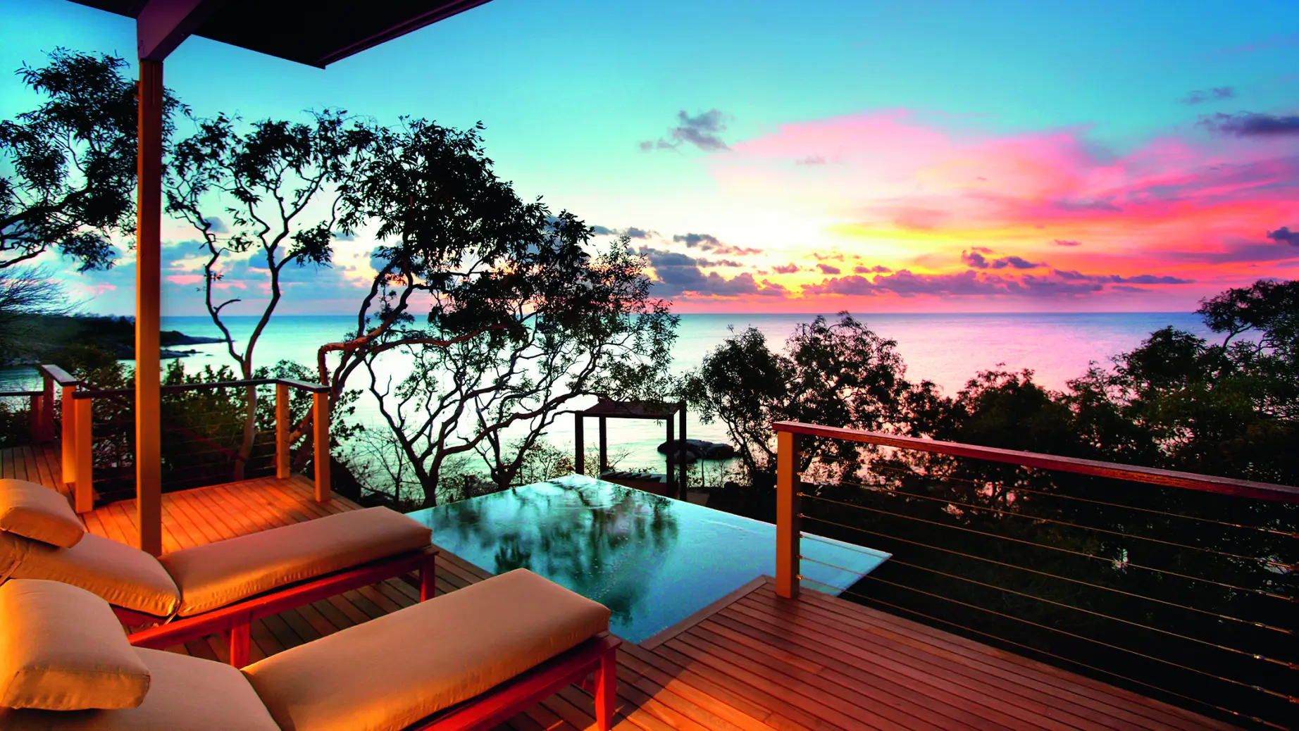 Liegestühle auf einer Terrasse mit Swimmingpool, bunter Himmel im Hintergrund - Australien