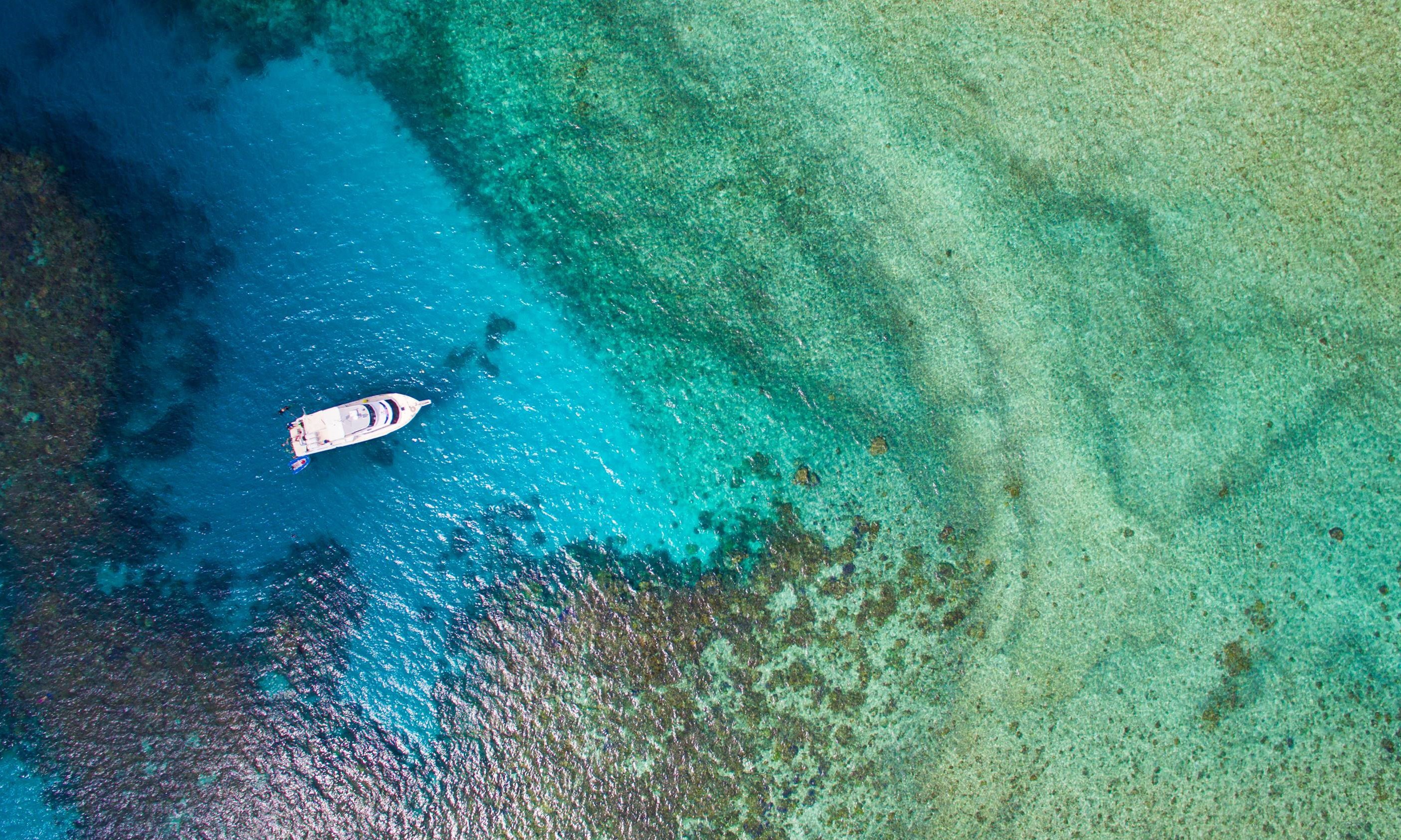 Weißes Boot bei Mission Beach in blau- und grünfarbenem Wasser