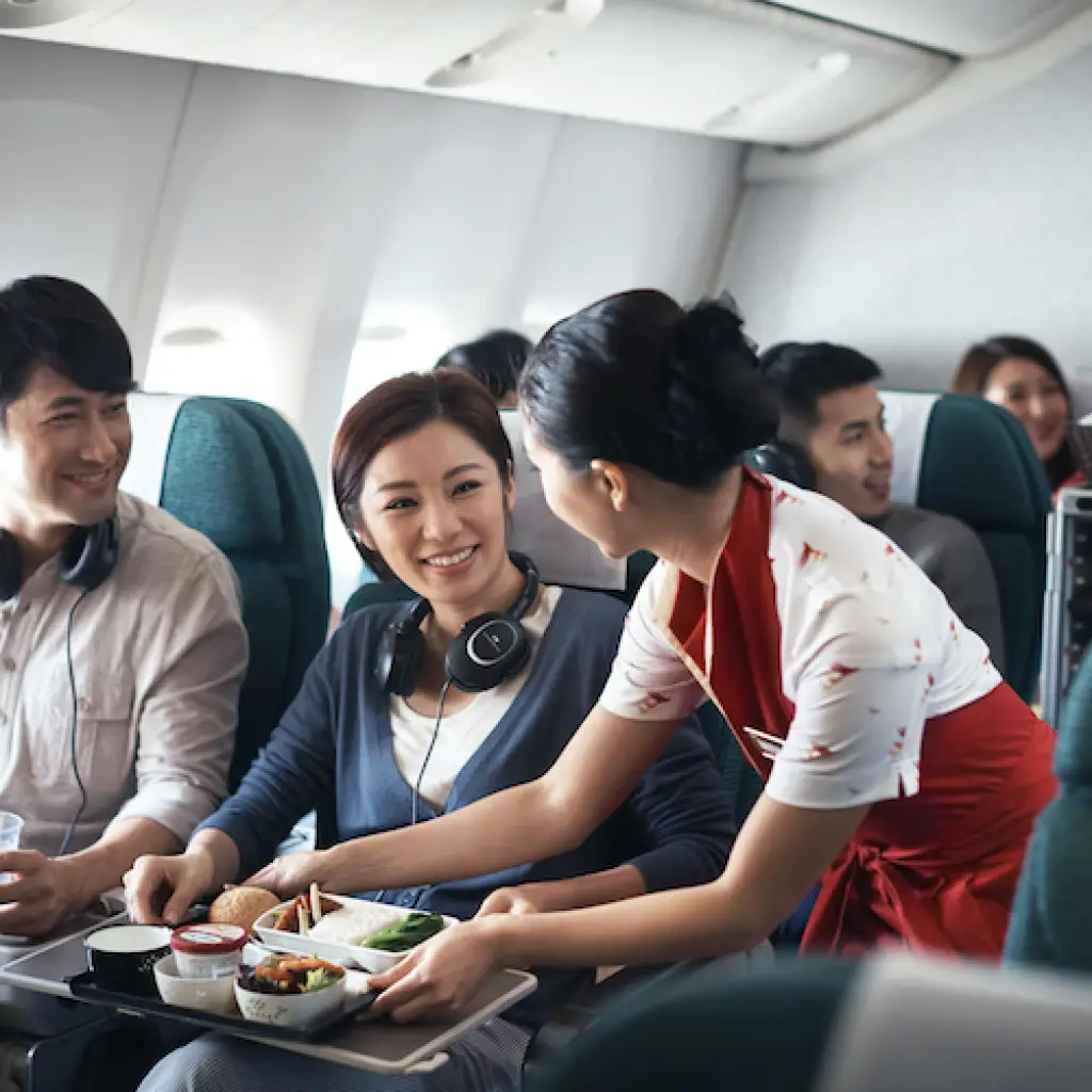 Stewardess der Fluggesellschaft Cathay Pacific serviert Passagieren ihre Mahlzeiten