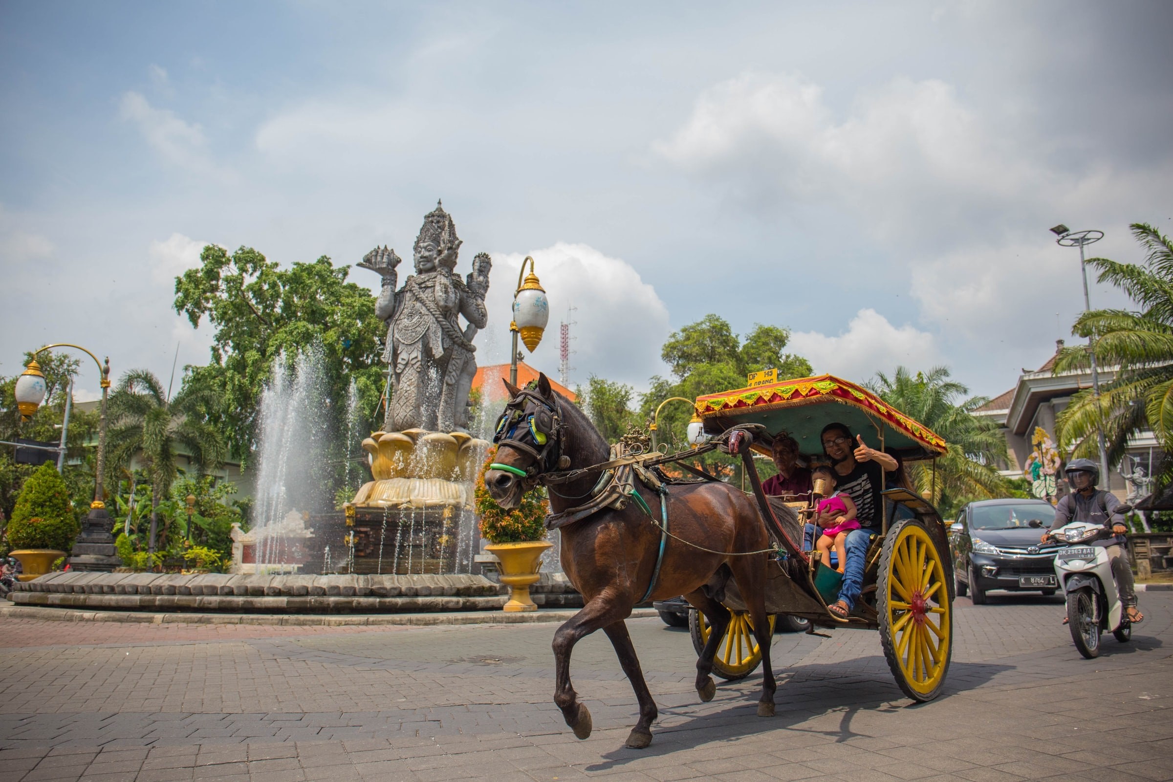 Mensen vervoeren per paardenkar met waterfundatie op de achtergrond in Bali