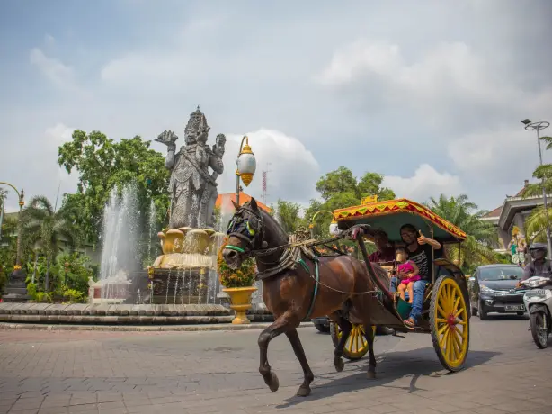 Mensen vervoeren per paardenkar met waterfundatie op de achtergrond in Bali