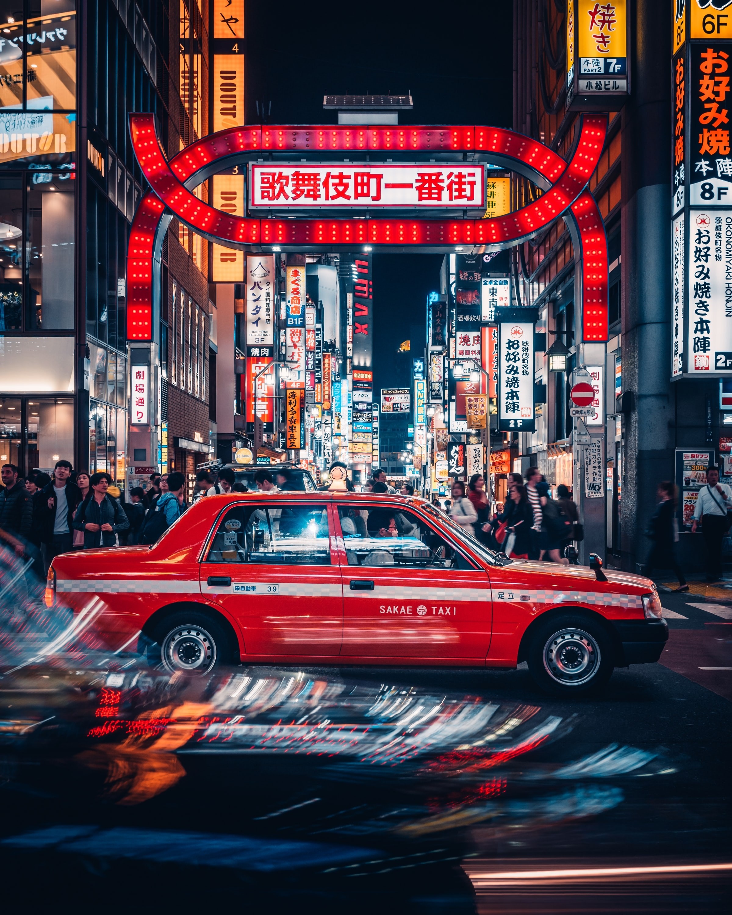 Ein Taxi fährt auf den Straßen von Tokio mit belebten Straßen und Lichtzeichen im Hintergrund