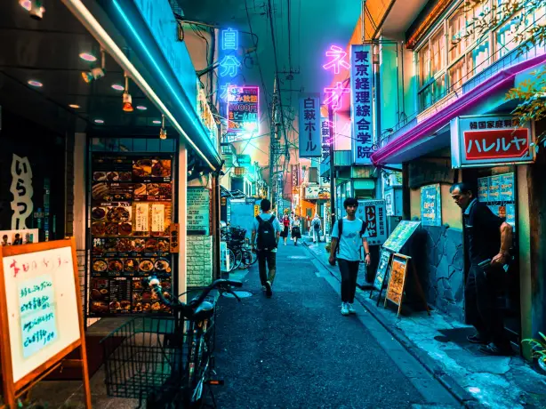 Busy street alley with neon lights at night in Tokyo