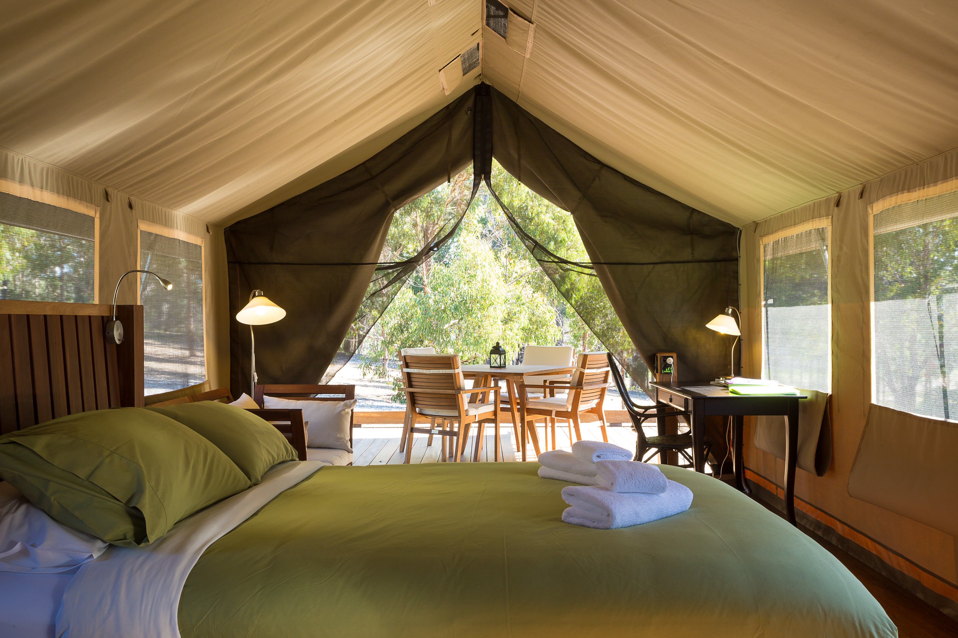 Innenraum eines Glamping-Safarizeltes mit einem Doppelbett, Sofa, Schreibtisch und Essbereich
