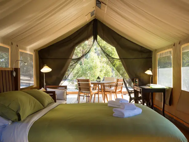 Innenraum eines Glamping-Safarizeltes mit einem Doppelbett, Sofa, Schreibtisch und Essbereich