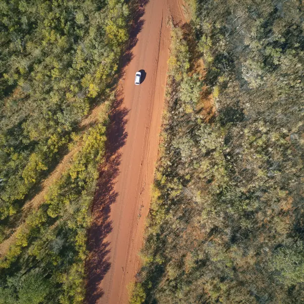 Luftaufnahme von Fahrzeug auf roter Sandpiste im australischen Outback