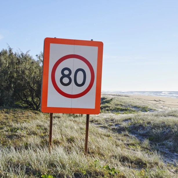 Verkeersbord met maximumsnelheid 80 km/u bij duinen en zee