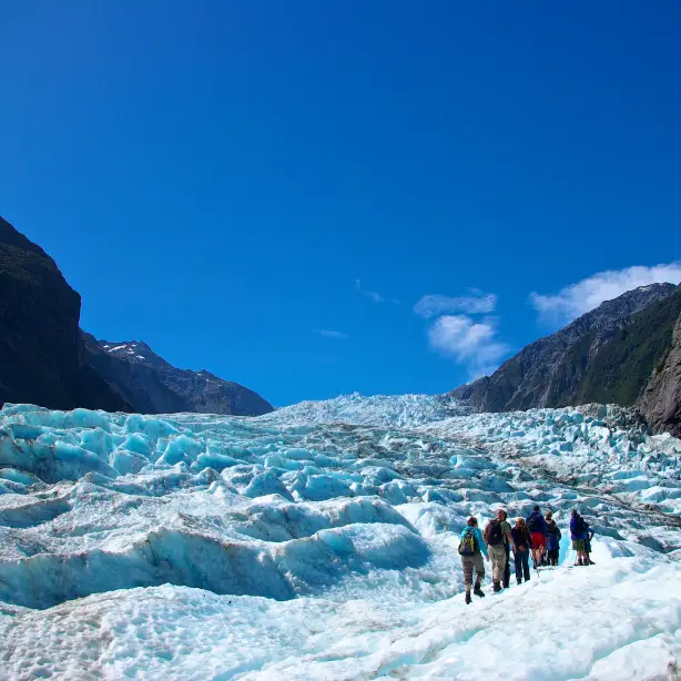 Wandelaars lopen over het blauwe ijs van Fox Glacier in Nieuw-Zeeland