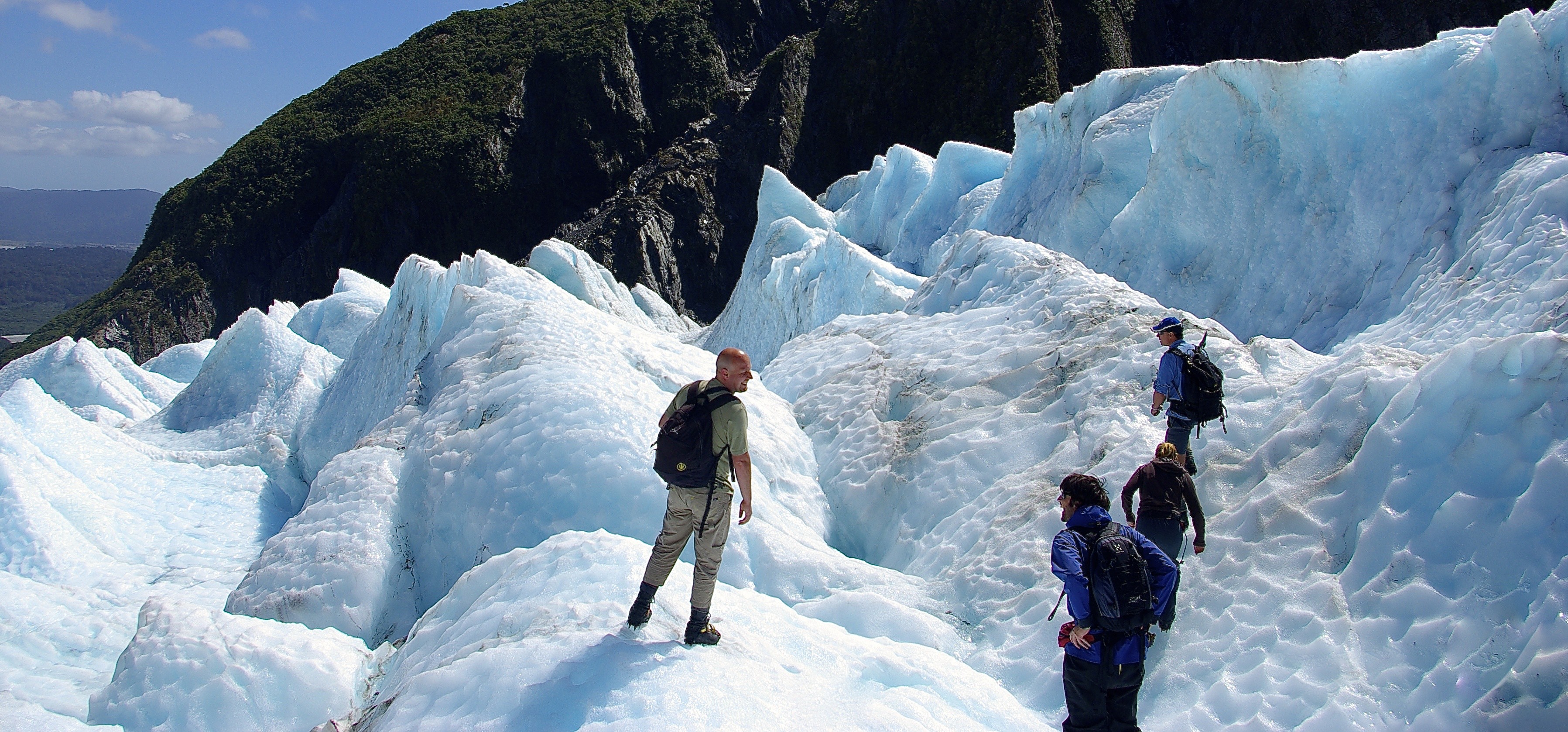 People walking over a snowy mountain in Franz Josef New Zealand