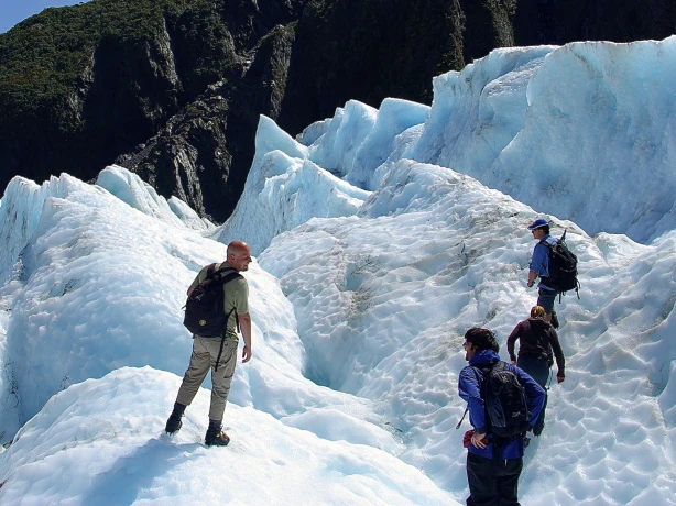 People walking over a snowy mountain in Franz Josef New Zealand