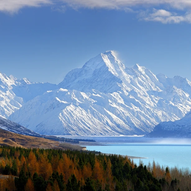 Een blauw meer en een boomgrens met grote besneeuwde bergen op de achtergrond in het Aoraki/Mount Cook National Park in Canterbury