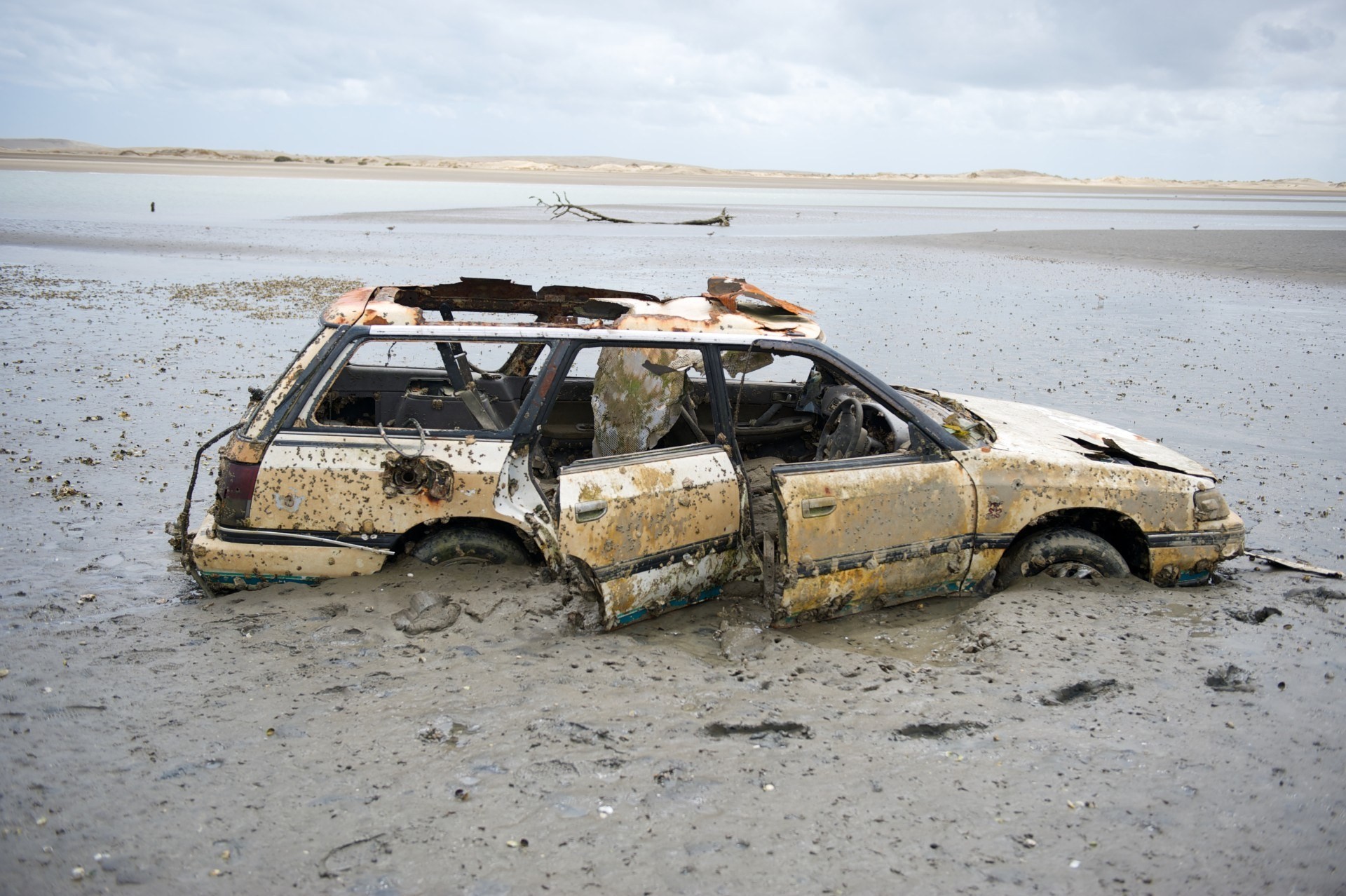 Het wrak van een auto op een strand in Nieuw-Zeeland
