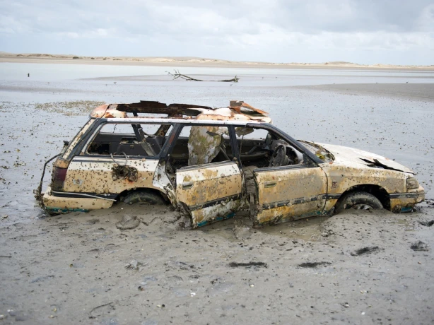 Het wrak van een auto op een strand in Nieuw-Zeeland