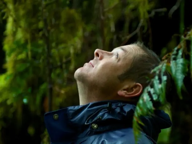 Andrew Morten looking up, surrounded by trees