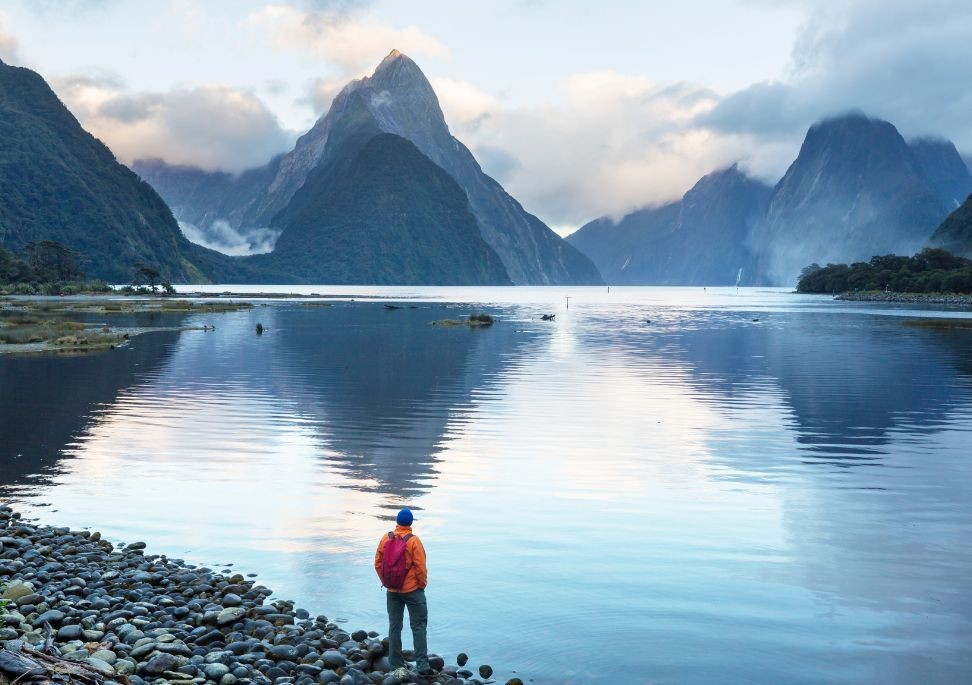 Ein Mann steht an der Küste des Milford Sound in Neuseeland