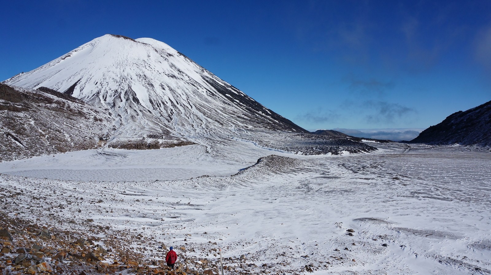 A man walks the Tongariro Alpine Crossing in New Zealand's North Island, which is blanketed in snow