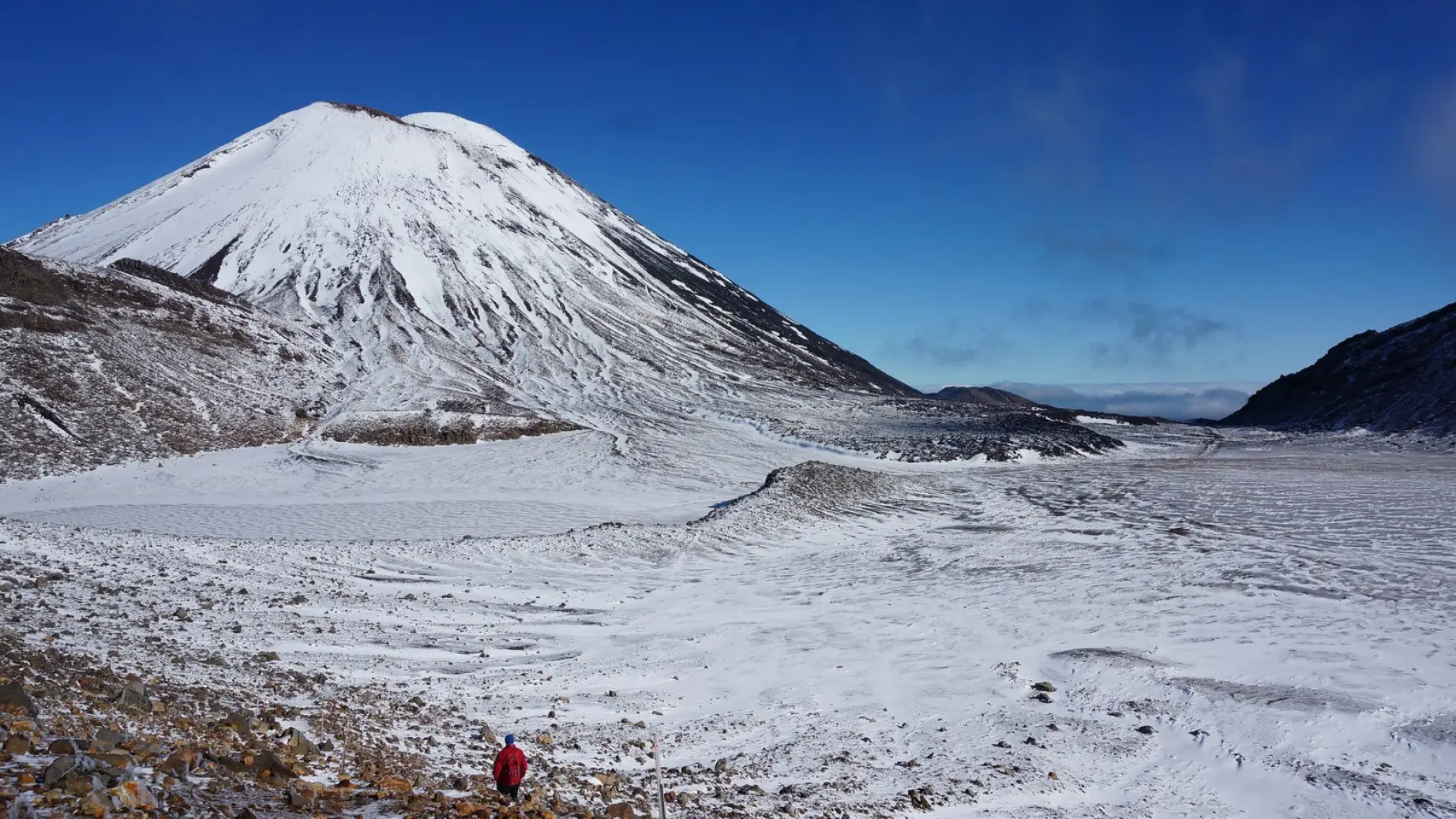 A man walks the Tongariro Alpine Crossing in New Zealand's North Island, which is blanketed in snow