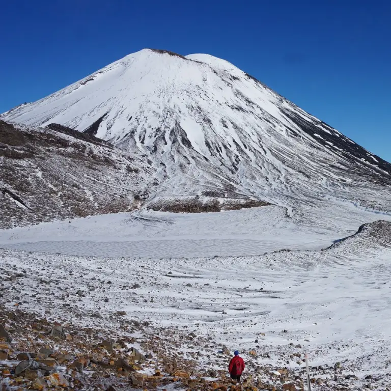 A man walks the Tongariro Alpine Crossing in New Zealand's North Island, which is blanketed in snow