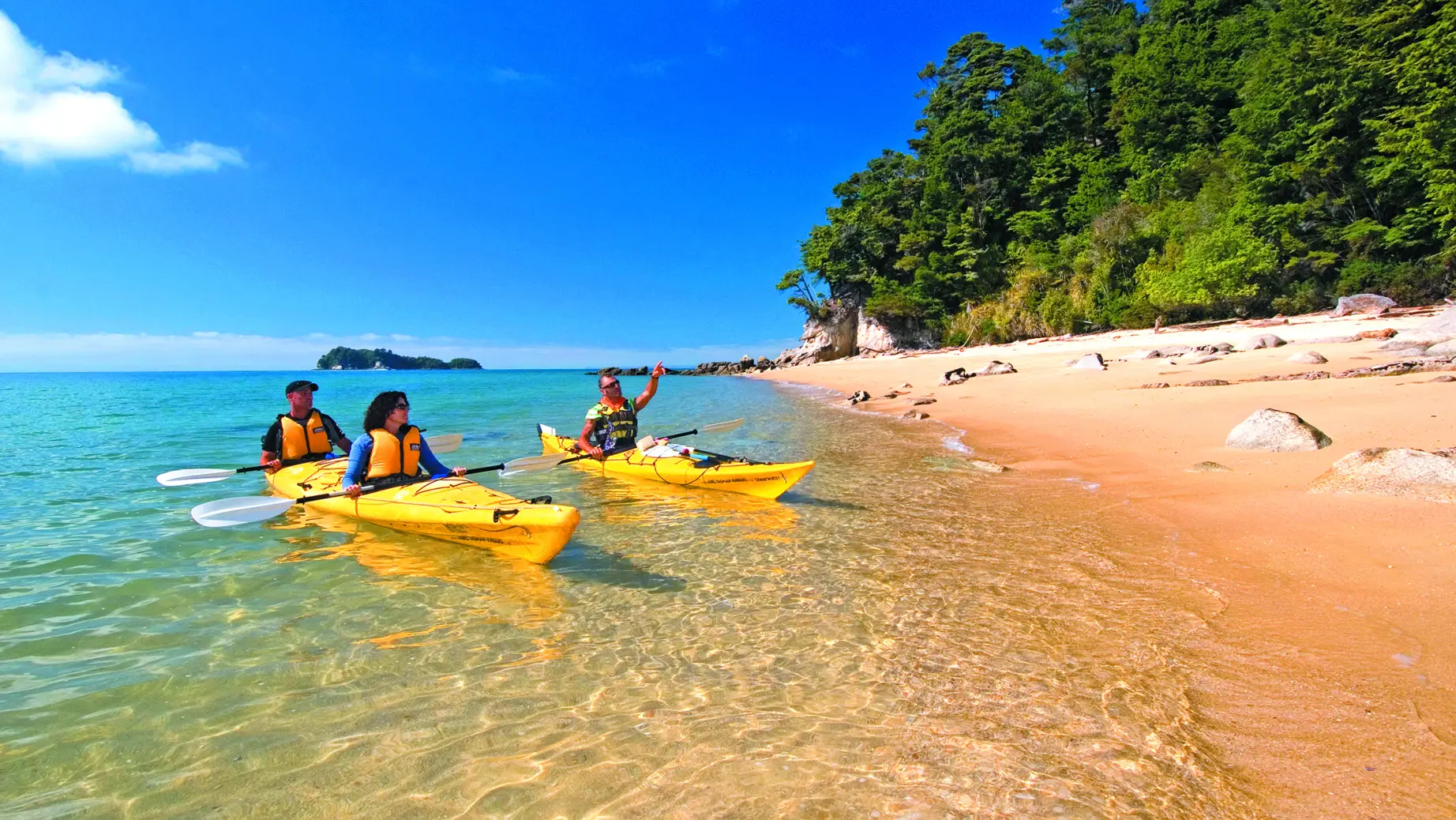 Zwei Kayaks mit drei Personen fahren an Strand