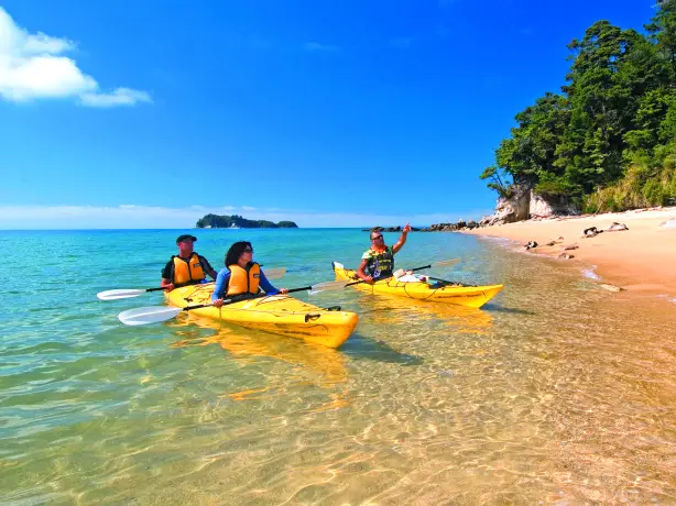Zwei Kayaks mit drei Personen fahren an Strand