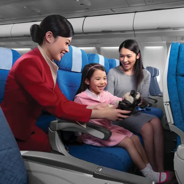Stewardess geeft een presentje aan een vrouw en een klein meisje in een vliegtuig