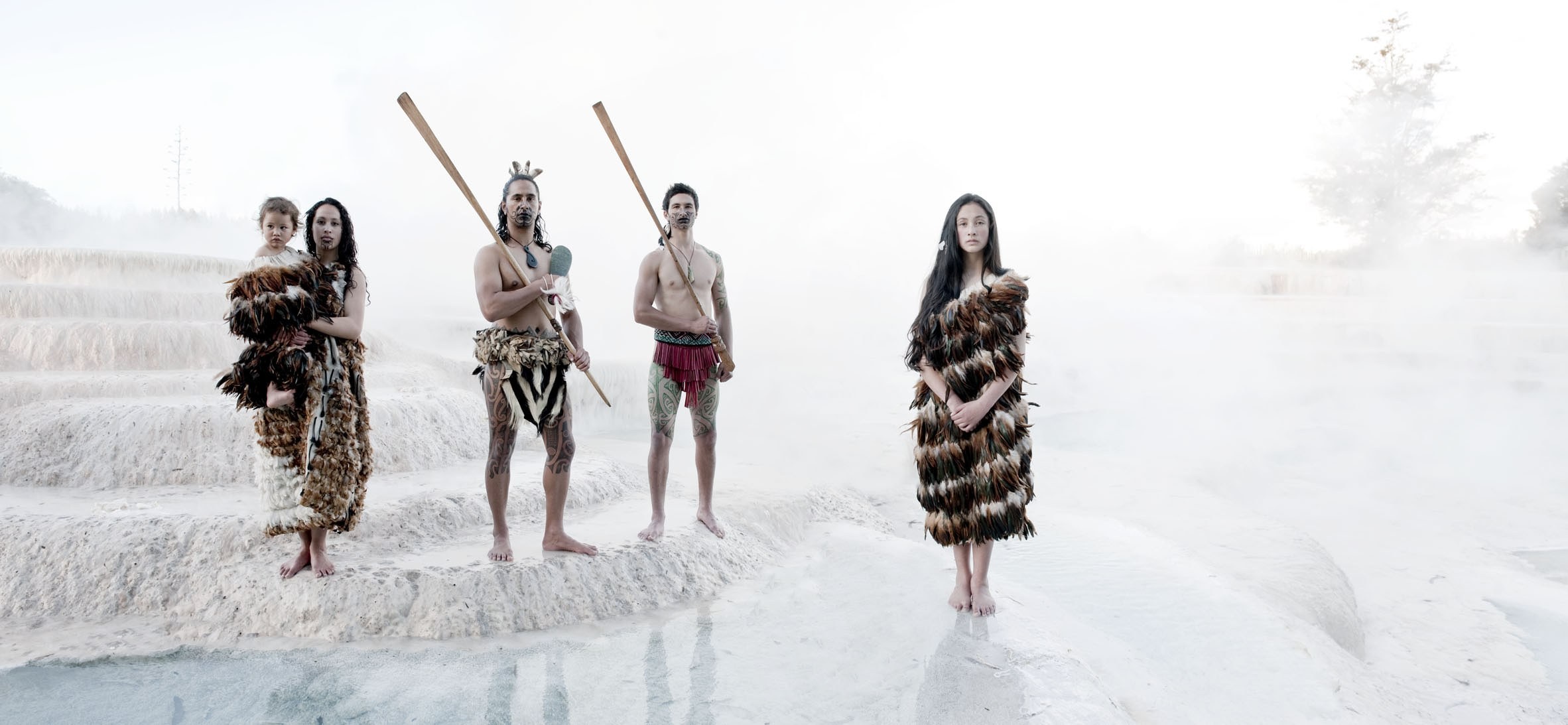 Eine Gruppe von Menschen in traditioneller Māori-Kleidung bei den weißen Wairakei Terrassen