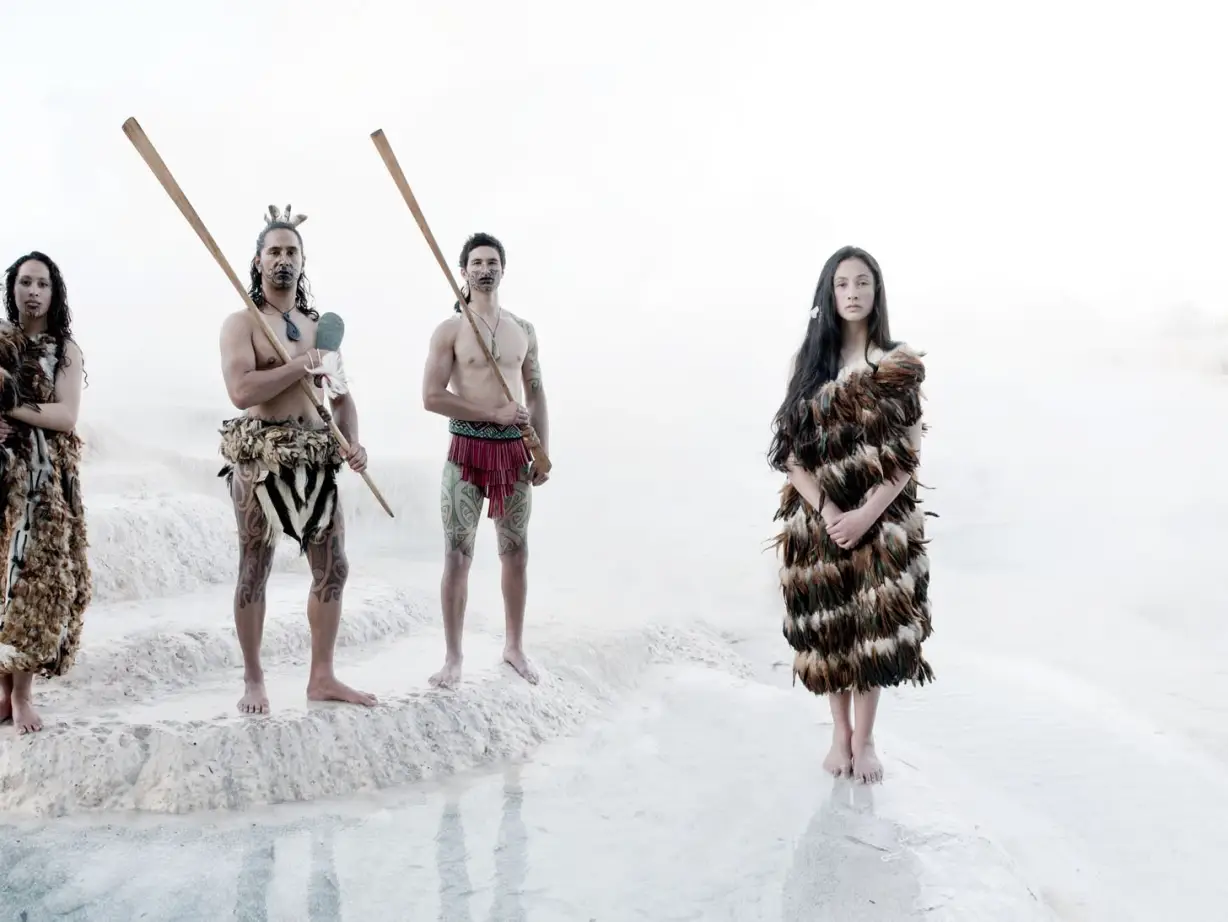 A group of people in traditional Māori clothing at the white Wairakei Terraces