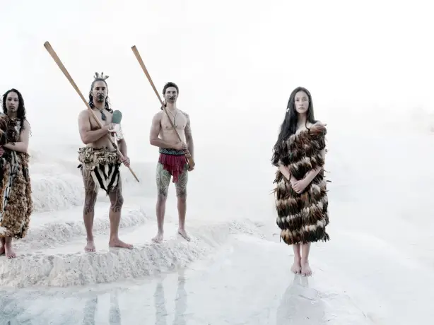 Eine Gruppe von Menschen in traditioneller Māori-Kleidung bei den weißen Wairakei Terrassen
