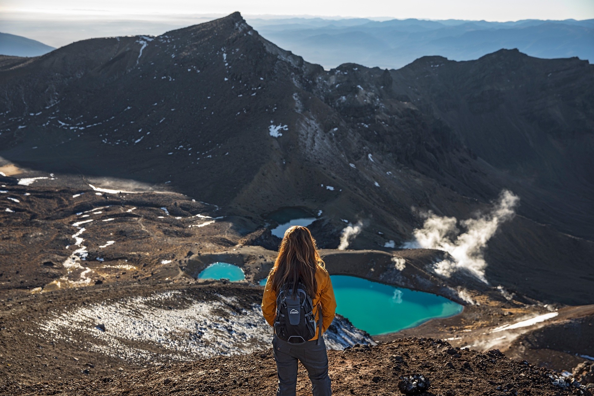 Eine Frau mit einem Rucksack blickt über das Tal im Tongariro-Nationalpark in Neuseeland