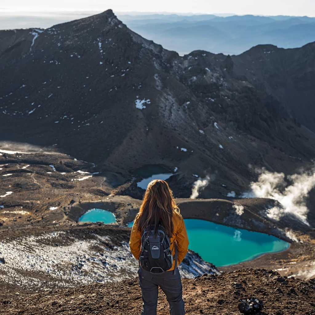 Eine Frau mit einem Rucksack blickt über das Tal im Tongariro-Nationalpark in Neuseeland