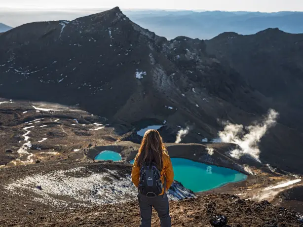 A woman with a backpack looking over the valley in Tongariro National Park in New Zealand