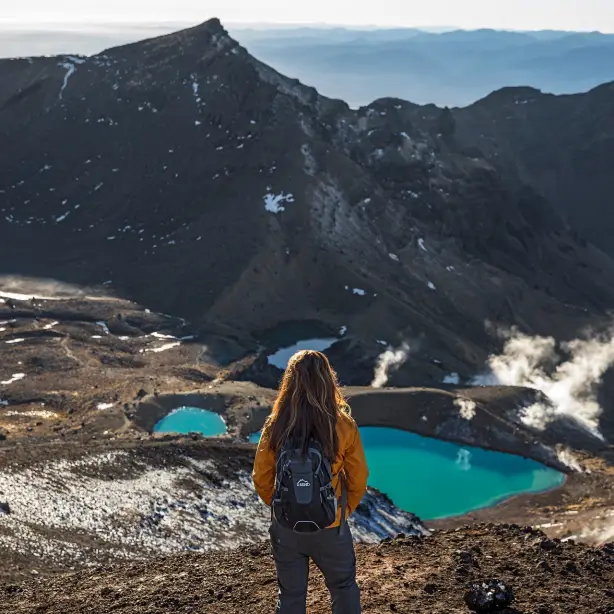 Eine Frau mit einem Rucksack blickt über das Tal im Tongariro-Nationalpark in Neuseeland